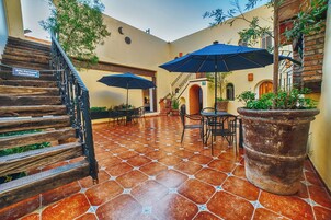 Un patio con escaleras de madera, mobiliario exterior y plantas en macetas.
