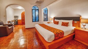 A hotel room with a large bed, wooden flooring, a desk, and a chair. - Hotel Casa Tequis San Luis Potosi (San Luis Potosi)