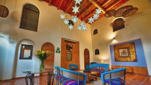 A spacious lobby with a high ceiling, a glass table, wicker chairs, and a decorative star hanging from the ceiling. - Hotel Casa Tequis San Luis Potosi (San Luis Potosi)