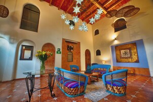 Un vestíbulo espacioso con techo alto, una mesa de vidrio, sillas de mimbre y una estrella decorativa colgando del techo.