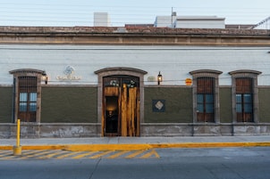 Un edificio con una puerta de madera grande, un letrero que dice "CASA TEQUIS" y una farola.
