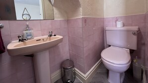 Un baño con lavamanos, inodoro y cubo de basura.