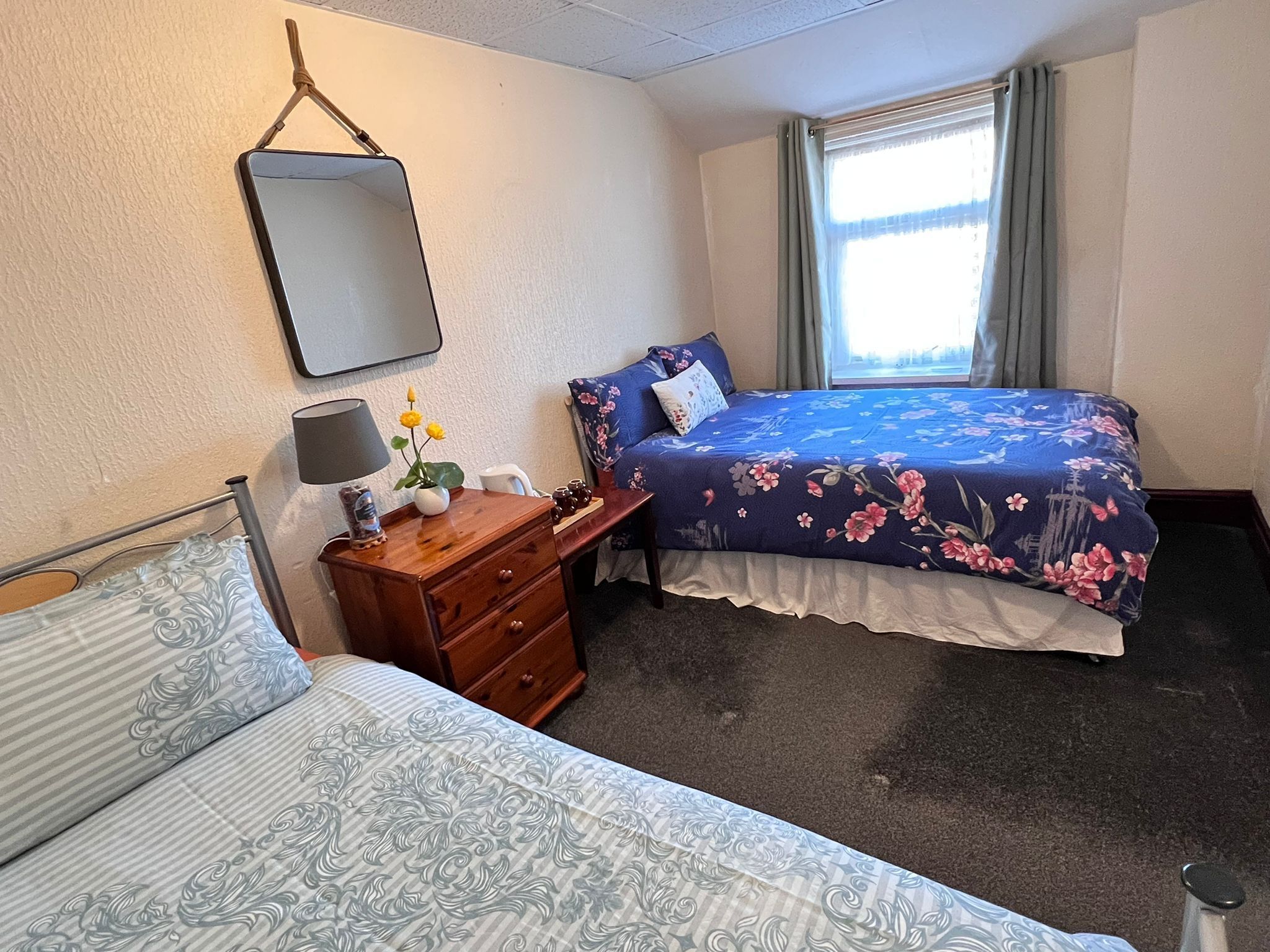 Une chambre à coucher avec un lit, une table de chevet avec une lampe, une commode et un miroir au mur.