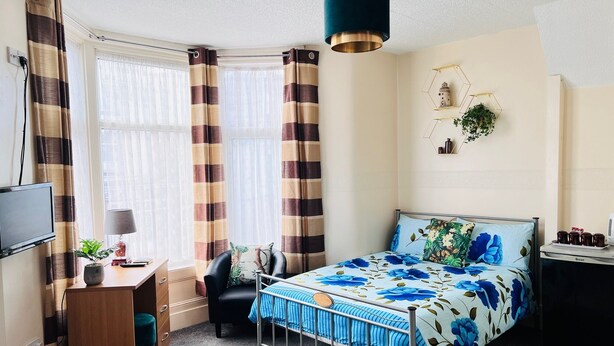 Un dormitorio con cama, escritorio, silla y televisor.