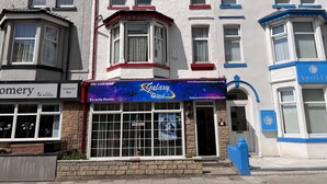 Un hotel con un llamativo letrero que dice 'Galaxy Hotel', una entrada visible y un anuncio de 'Habitaciones disponibles'.