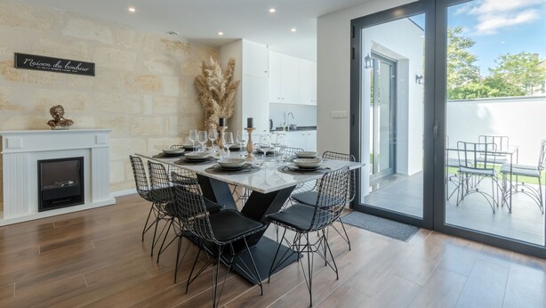 Un comedor moderno con chimenea, mesa para seis personas y vista del patio exterior.