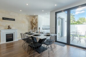 A modern dining area with a fireplace, dining table set for six, and a view of the outdoor patio.