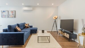 Una sala de estar moderna con un sofá modular, un televisor de pantalla plana, una mesa de centro y una lámpara de pie.