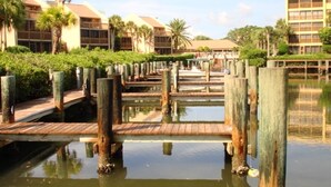 A waterfront hotel with wooden walkways over water, surrounded by greenery and palm trees. - Midnight Cove #714, Bayside in Siesta Key, FL, 2BR-1 1/2BA, 1st Floor (Sarasota)