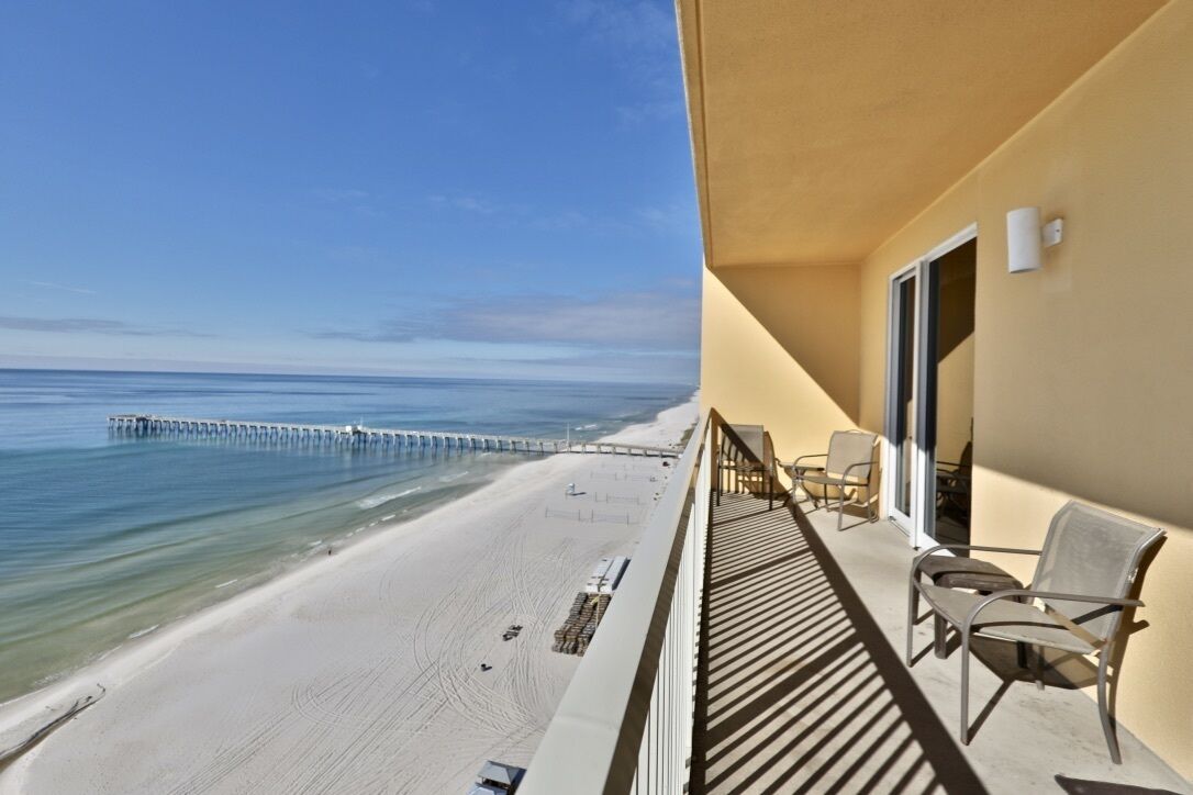 A balcony with a view of a beach and a pier.