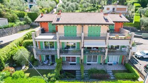 Ein mehrstöckiges Haus mit Ziegeldach, grünen Fensterläden und einem Balkon.