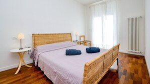 Ein Zimmer mit einem Bett, zwei Nachttischen, einem Sessel und einer Heizung.