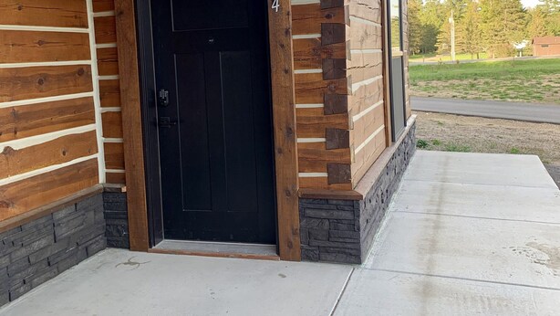 A building with a wooden exterior, a black door, and a concrete entrance area. - {Big Timbers} Lodging next to North Entrance of Itasca State Park (Shevlin)