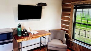 A room with a flat-screen TV mounted on the wall, a wooden desk with a chair, a microwave, and a coffee maker. - {Big Timbers} Lodging next to North Entrance of Itasca State Park (Shevlin)