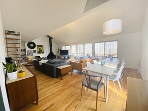 Uma sala de estar moderna com lareira, área de jantar e grandes janelas.