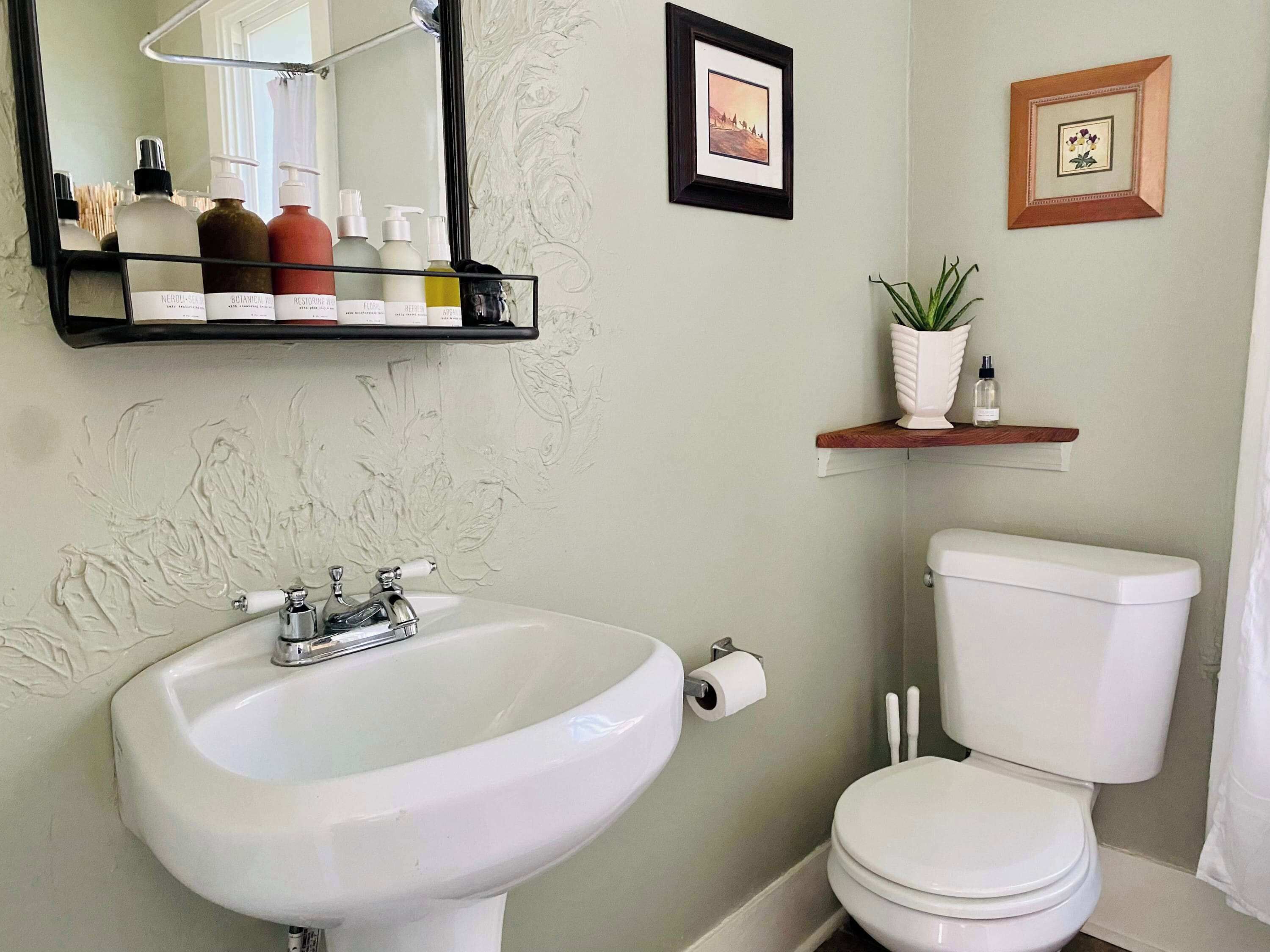A bathroom with a sink, toilet, and shelves with toiletries.