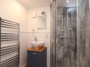 Un baño con cabina de ducha de vidrio, un lavabo con encimera de madera y un perchero para toallas.