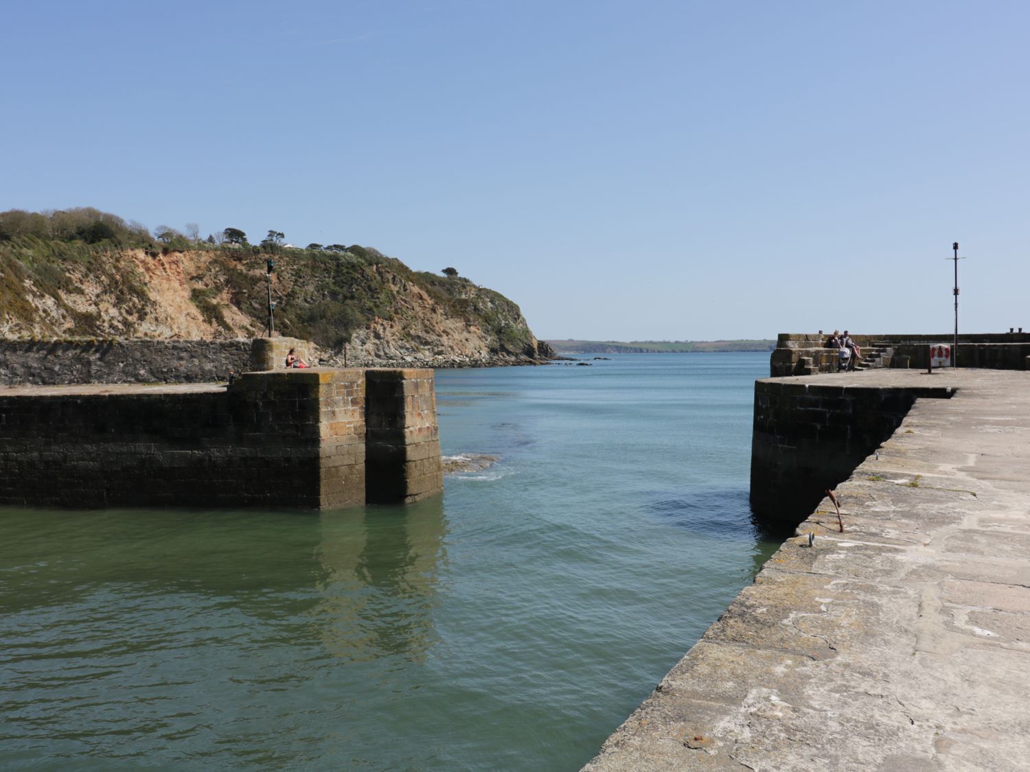 Un muelle costero con muros de piedra y una vista despejada del mar.