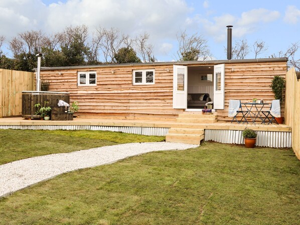 Una cabaña de troncos con un patio, un jacuzzi y una pequeña zona de estar al aire libre.
