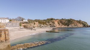 Una zona costera con una playa arenosa, un acantilado rocoso y un muro de piedra.