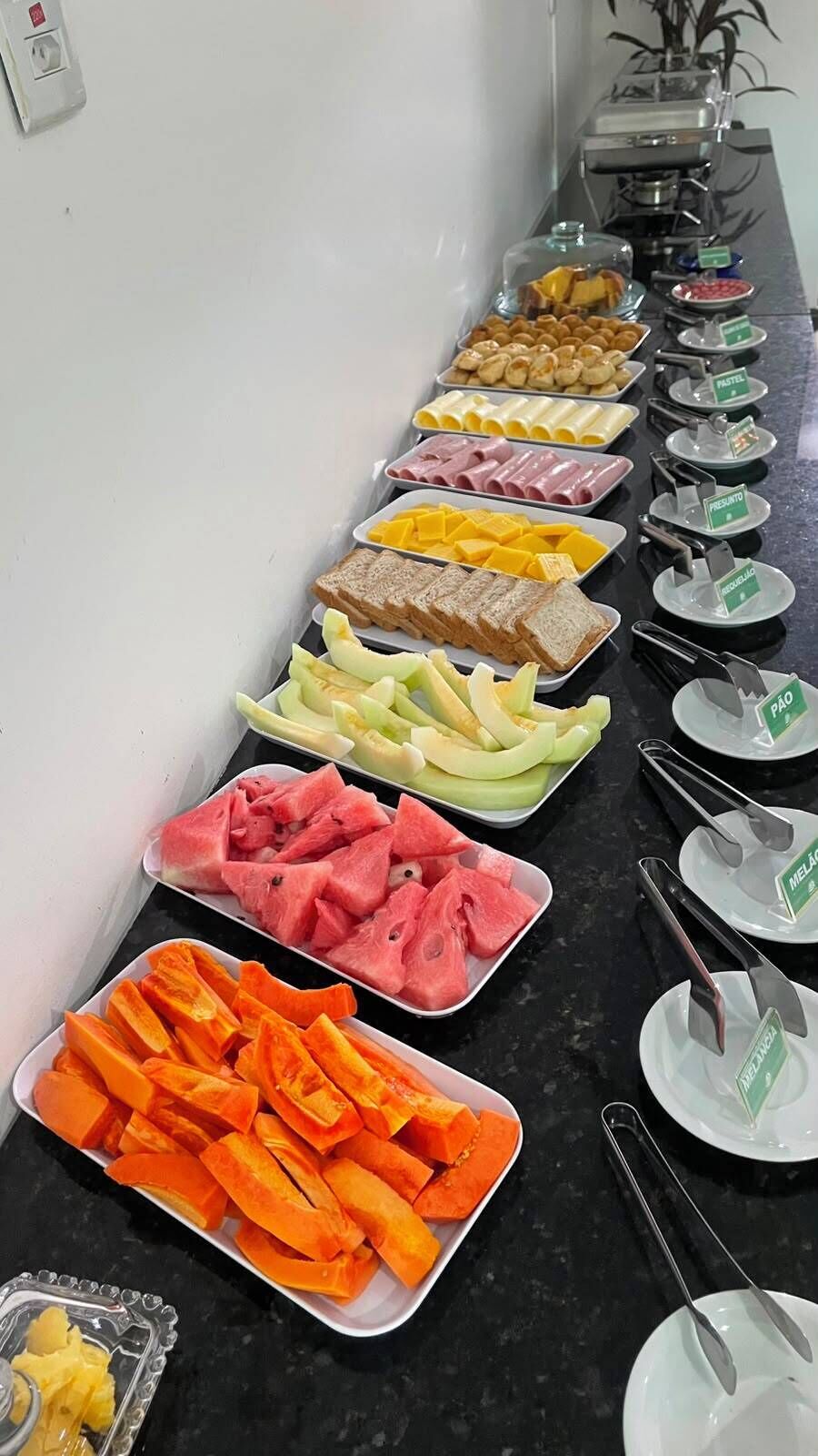 Een buffet met diverse etenswaren, zoals fruit, kazen en vlees.
