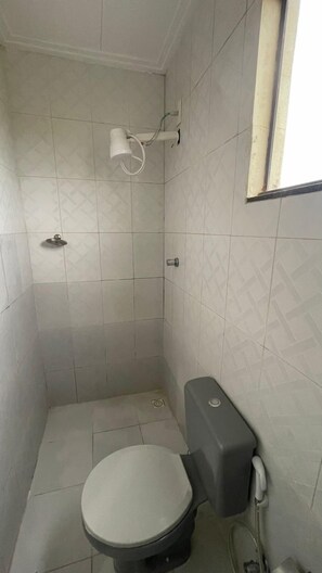 Um banheiro pequeno revestido com azulejos, com vaso sanitário, pia fixa na parede e janela.
