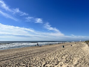 Een strand met heldere lucht, zand en enkele mensen.
