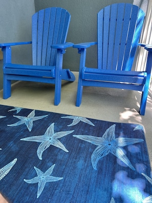 Two blue Adirondack chairs and a dark blue rug with starfish patterns.