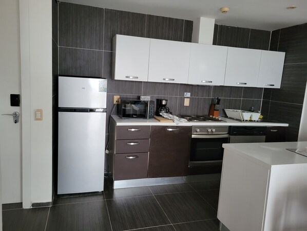 Una cocina moderna con refrigerador, microondas, estufa y armarios.