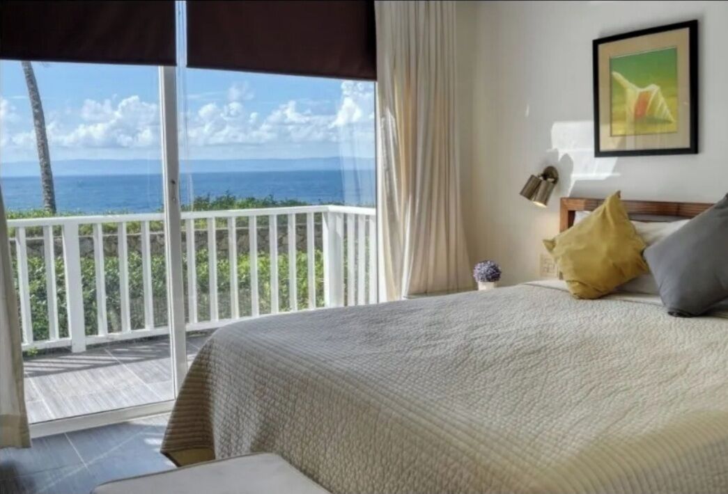 Une chambre dotée d’une grande fenêtre donnant sur l’océan et d’un balcon.