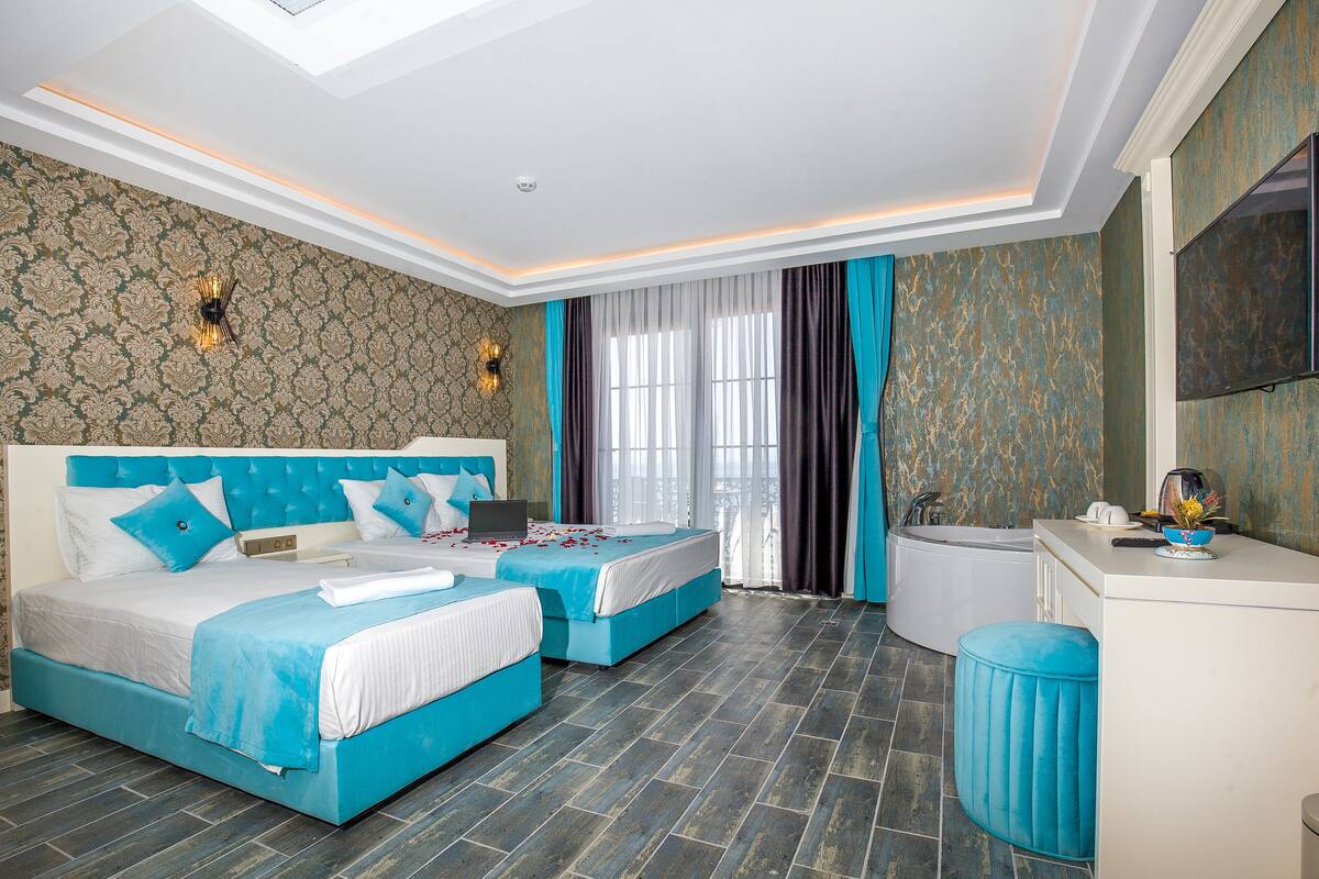 Quarto de hotel com duas camas, uma banheira e uma toucador com espelho.
