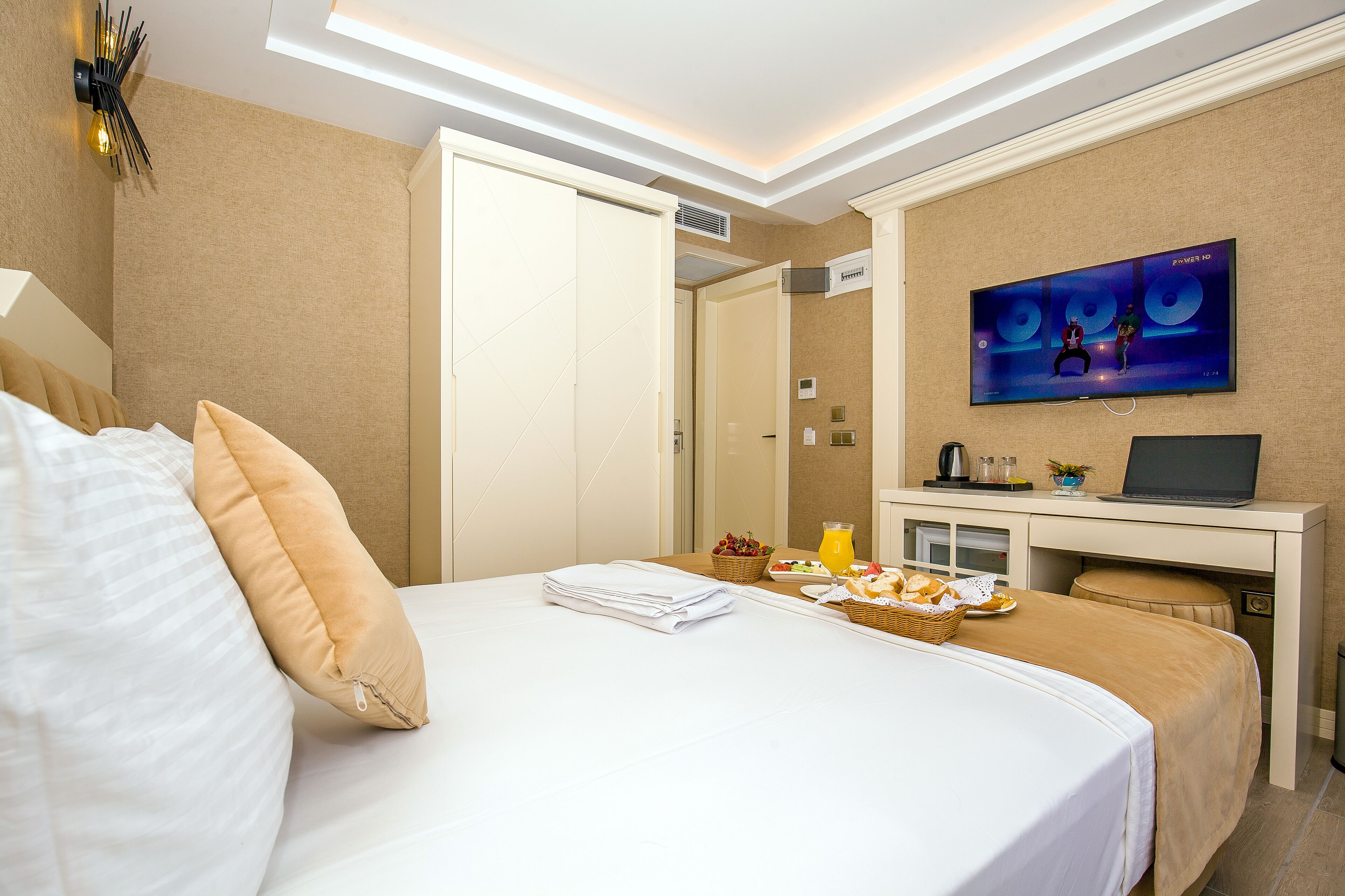 Une chambre d’hôtel équipée d’un lit, d’un bureau avec un ordinateur portable, d’une télévision et d’un plateau de petit-déjeuner.
