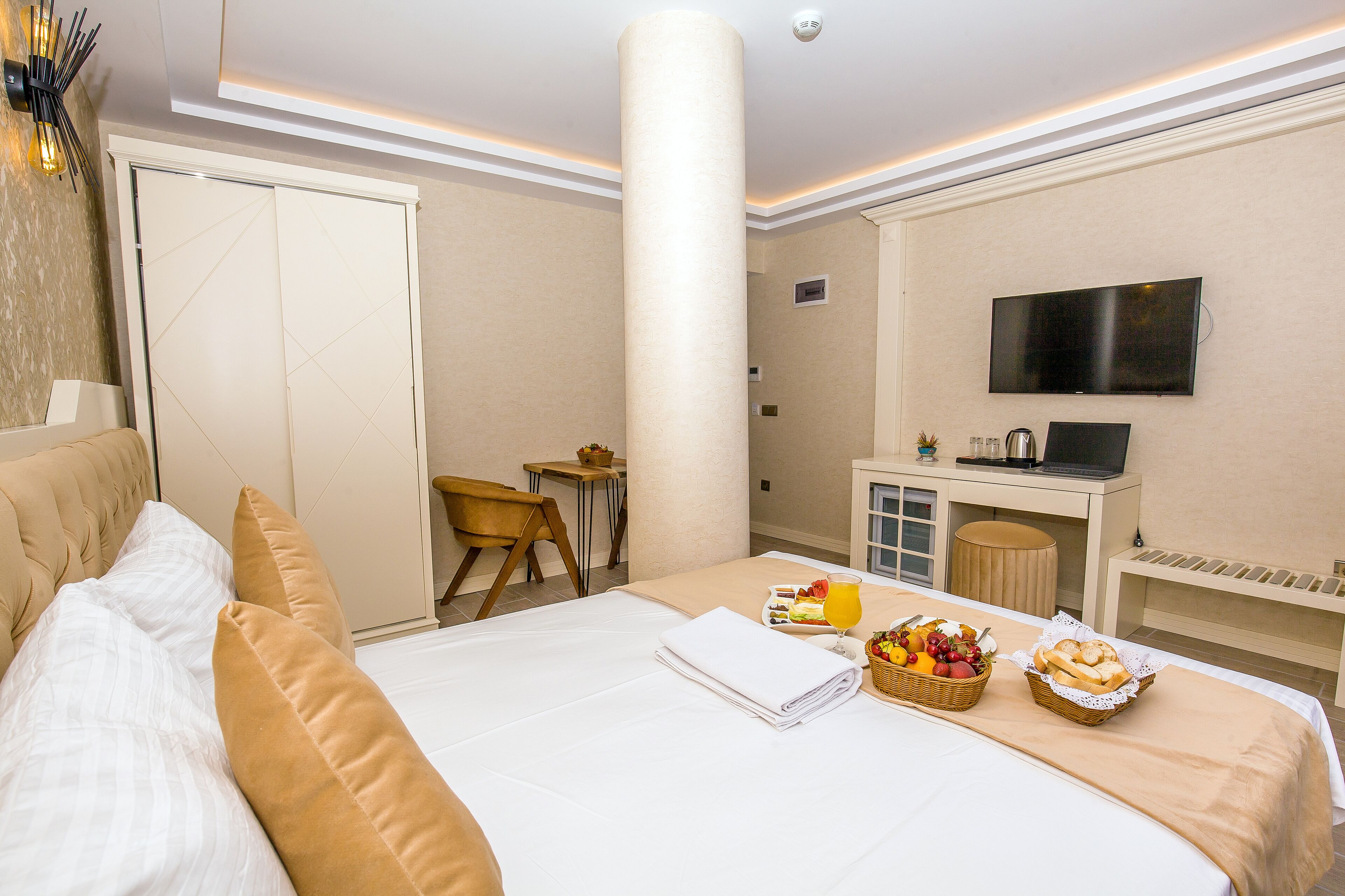 Una habitación de hotel con cama, escritorio, televisor y bandeja de desayuno.