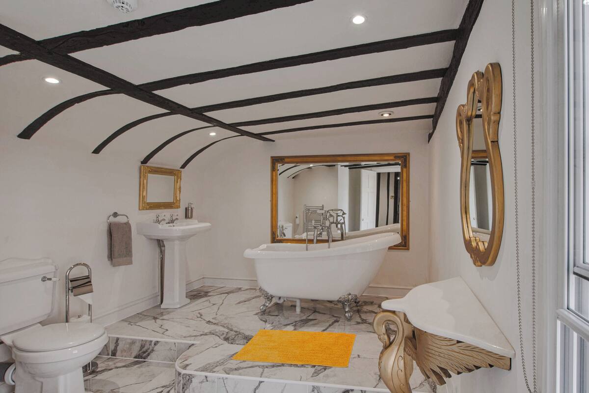 Ein Badezimmer mit Badewanne, Toilette, Waschbecken und Spiegeln.