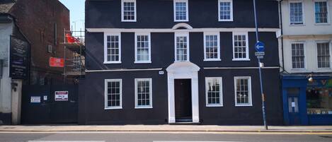 A two-story building with a black facade and white trim, featuring a central entrance with a white archway.