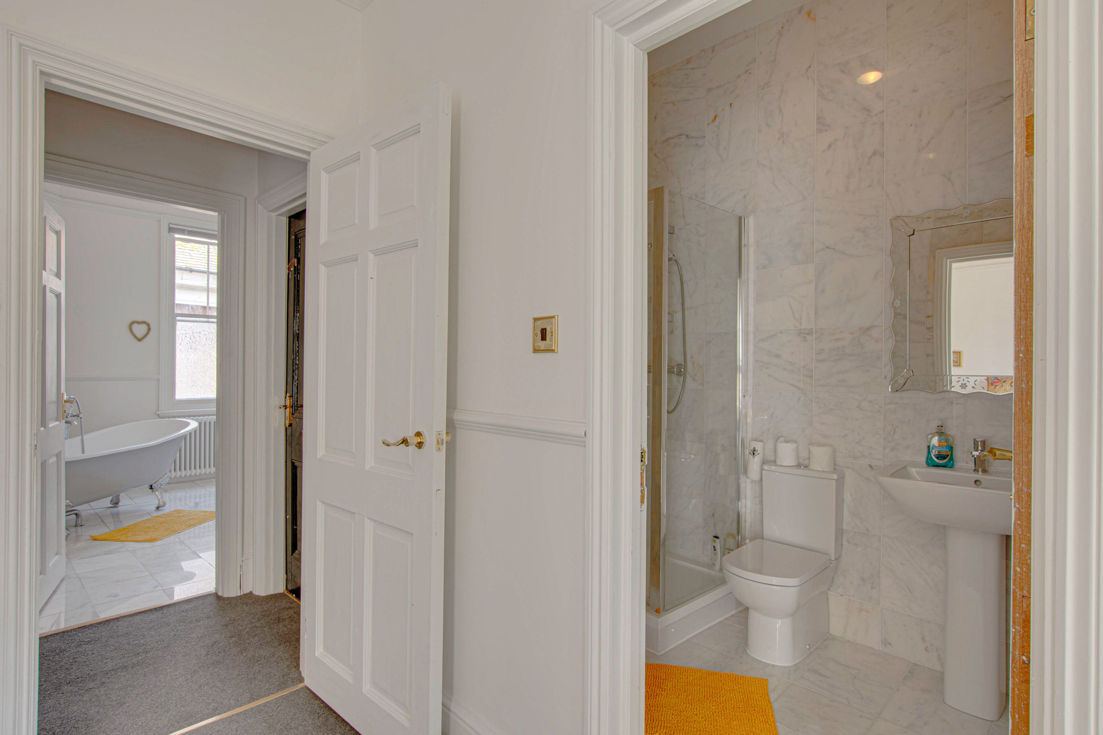 Et badeværelse med badekar, toilet og brusebad.