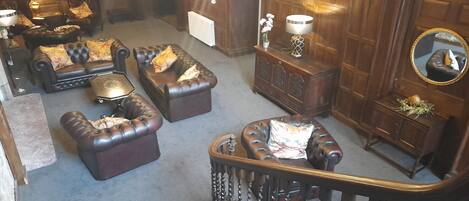 Un salon spacieux avec des canapés en cuir, un meuble en bois et un escalier.
