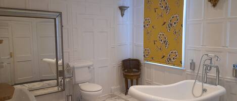 A bathroom with a freestanding bathtub, a toilet, and a shower area.