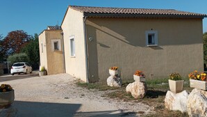 A two-story building with a tiled roof, a gravel driveway, and flower planters. - VILLA WITH HEATED SWIMMING POOL JACCUZI SAUNA (Barjac)