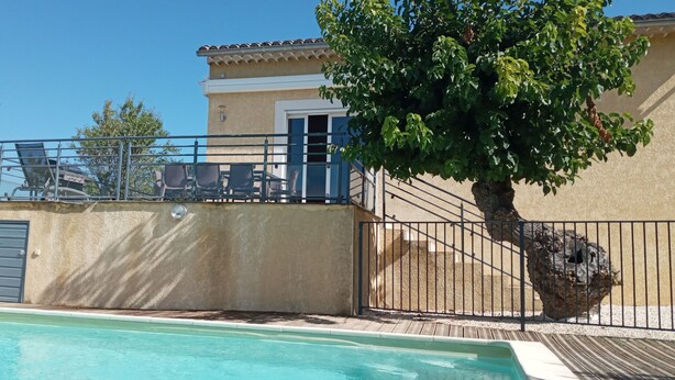 A poolside area with a clear view of the pool, a metal railing, and a building with a door and windows. - VILLA WITH HEATED SWIMMING POOL JACCUZI SAUNA (Barjac)