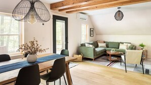Un espacio habitable estilo loft con comedor, un sofá verde y techo de madera.