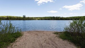 Una playa arenosa que da a un lago tranquilo con orilla arbolada.