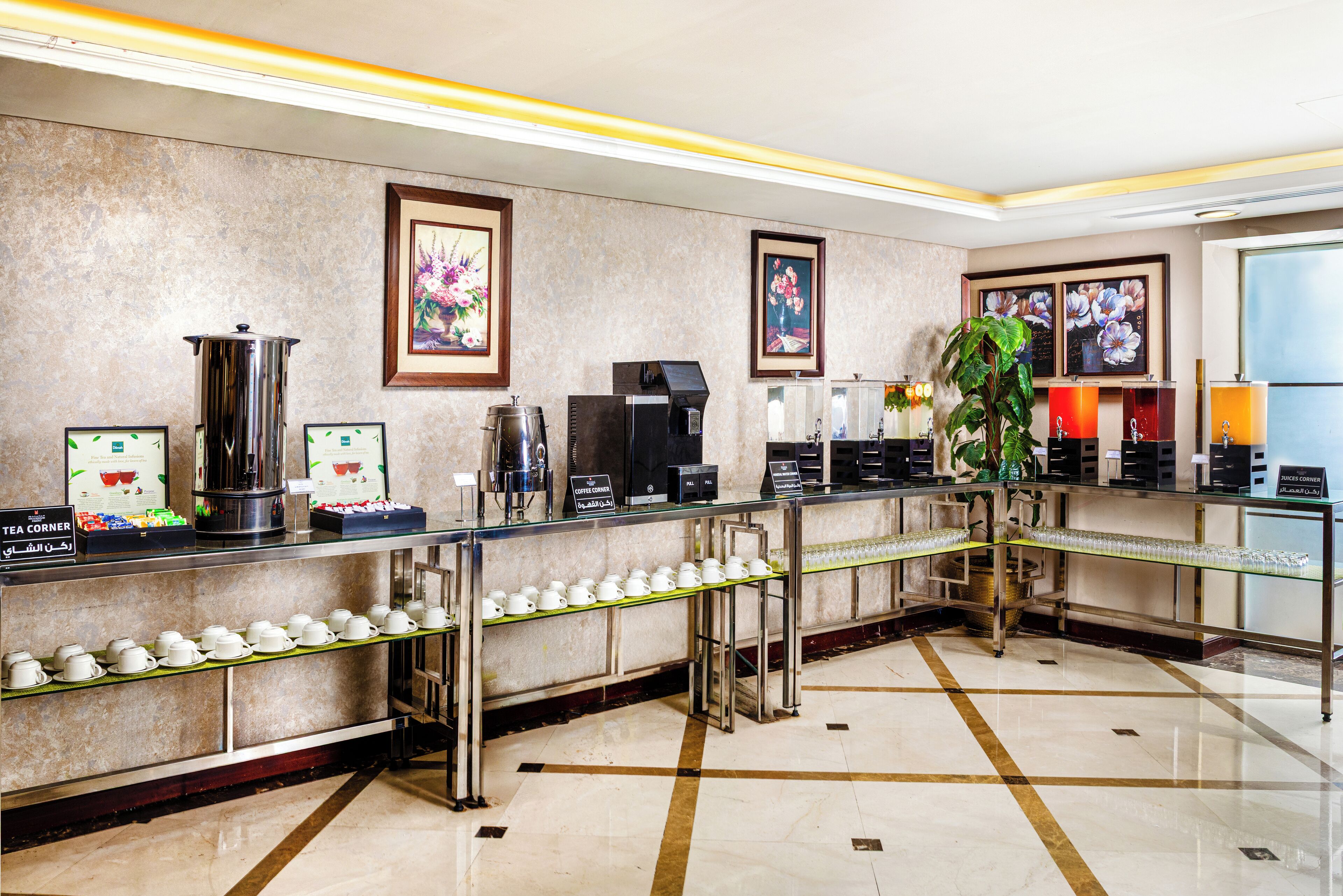 Eine Hotlellobby mit einer Kaffeestation, einer Tee-Ecke und gerahmten Kunstwerken an den Wänden.