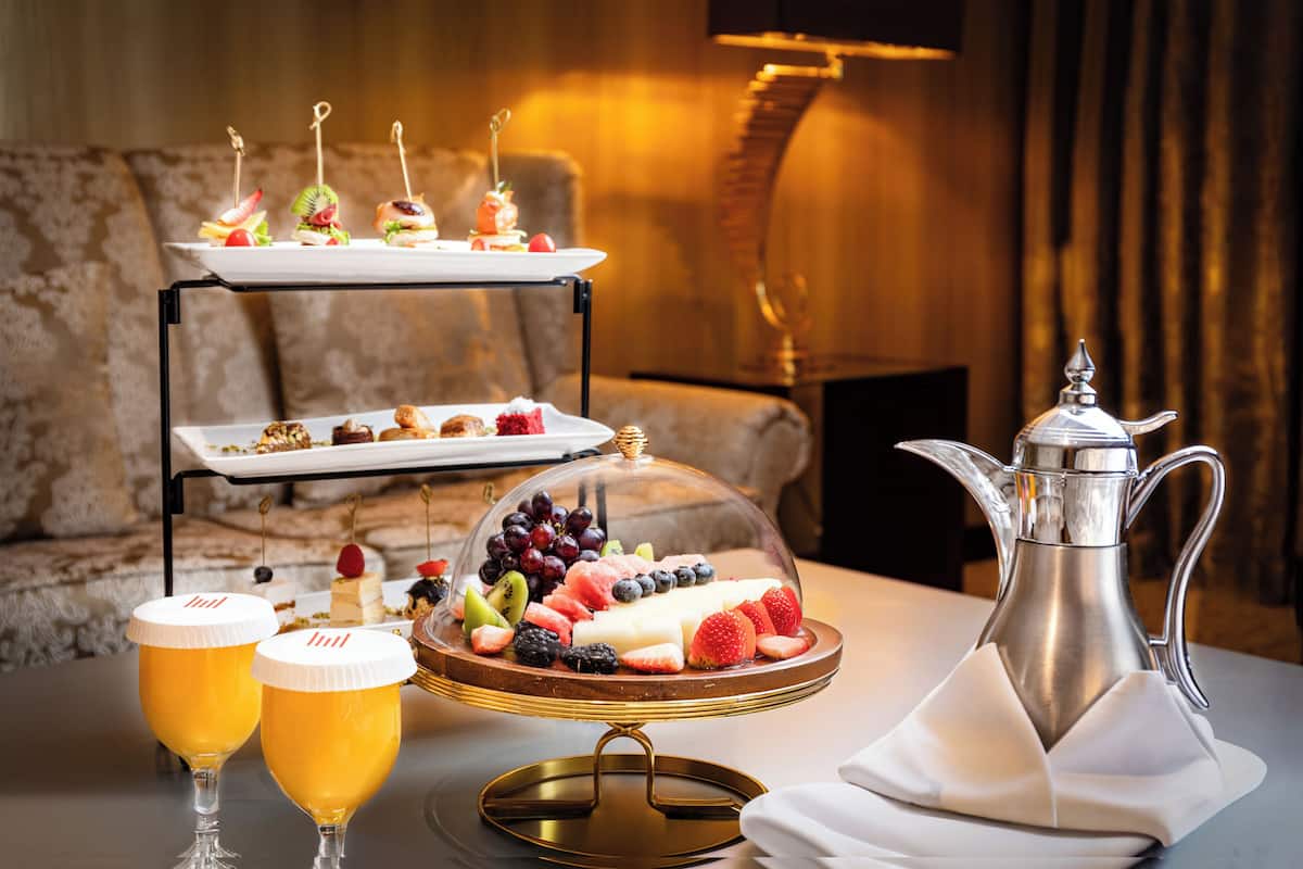 Une table de desserts avec un assortiment de pâtisseries et de fruits, deux verres de bière et un pichet en argent.