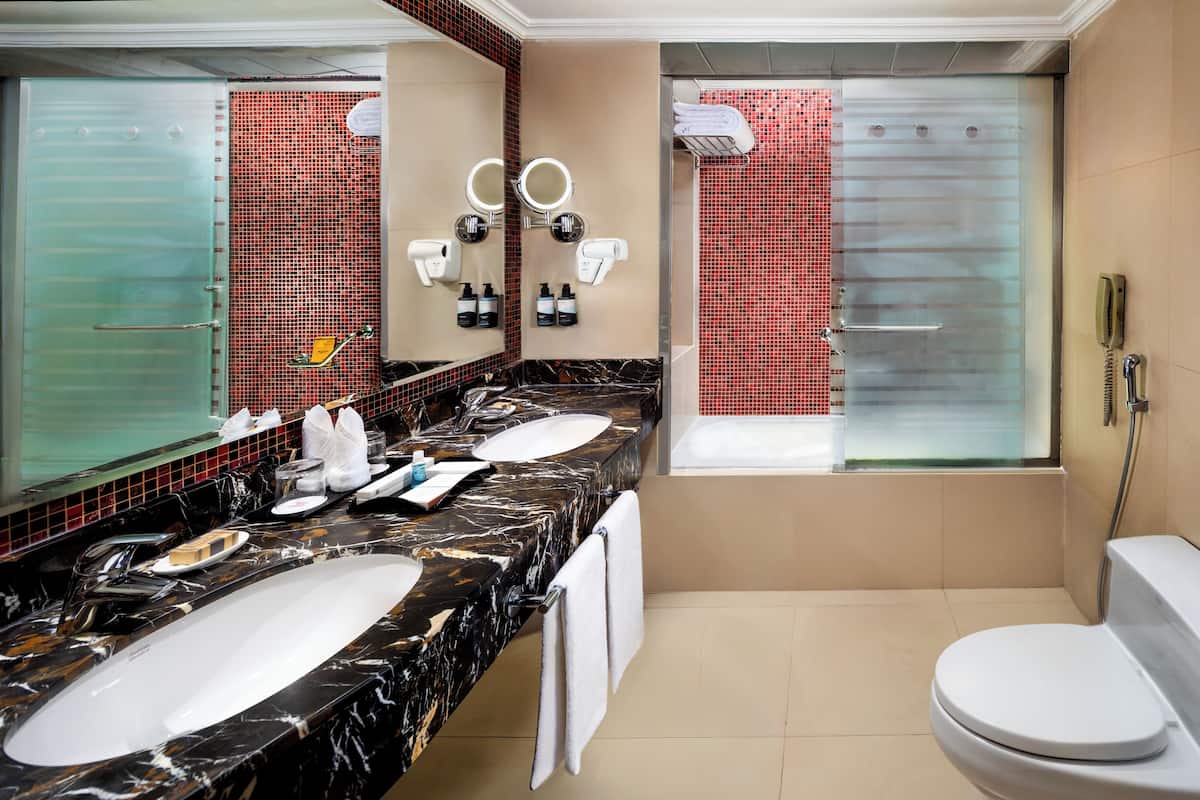 Une salle de bain moderne avec un grand miroir, deux lavabos, des toilettes et une douche.
