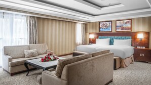 Een hotelkamer met een groot bed, een bank, een bijzettafeltje met bloemen en een schilderij aan de muur.