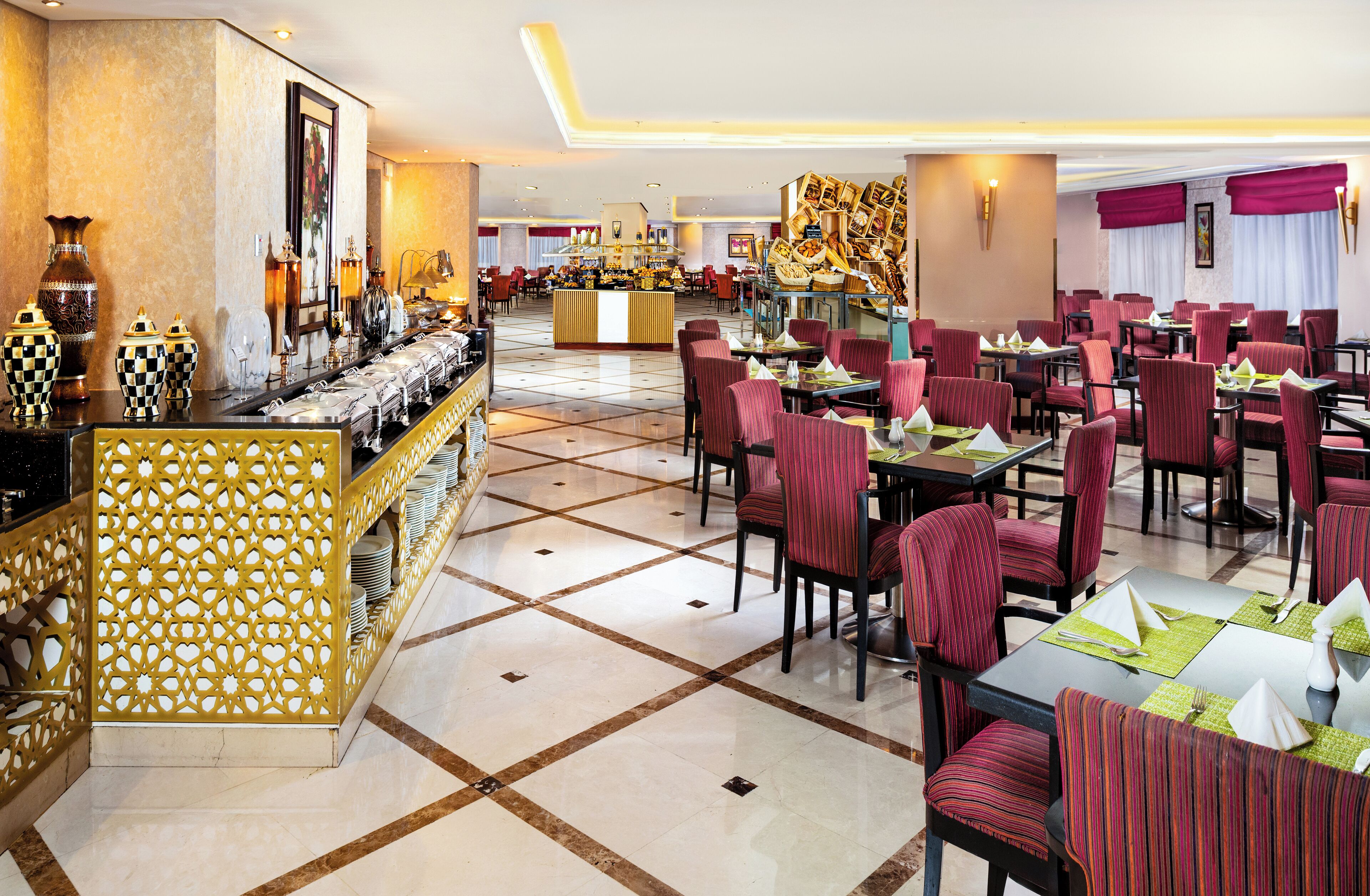 A spacious restaurant with multiple dining tables and chairs, a decorative counter with vases, and a tiled floor.