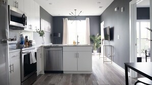 A modern kitchen with stainless steel appliances, a central island, and a dining area with a black table. - Cozy New-Built Home in Downtown Atlanta (Atlanta)