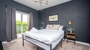 A bedroom with a bed, a nightstand, a wall-mounted light fixture, and a window with curtains. - Cozy New-Built Home in Downtown Atlanta (Atlanta)