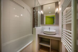 A modern bathroom with a bathtub, a sink, and a mirror.